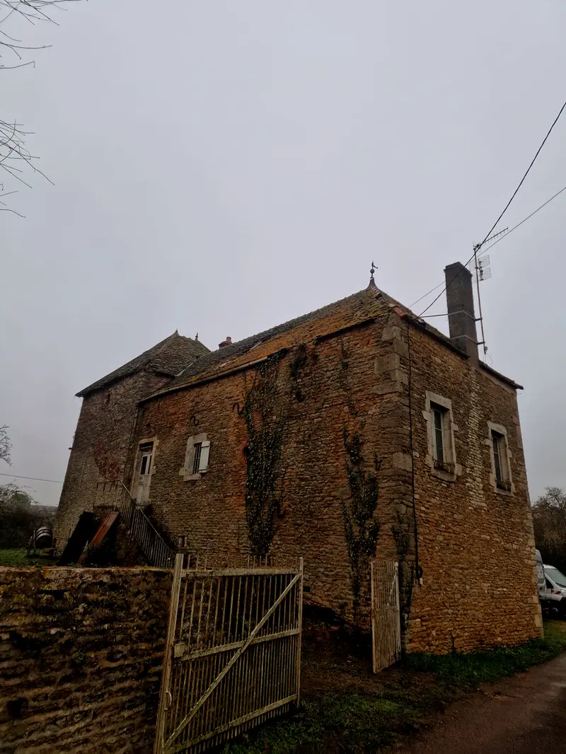 Le moulin avant travaux vu depuis la route, deux corps en pierre accolés, escalier extérieur et portail de bois